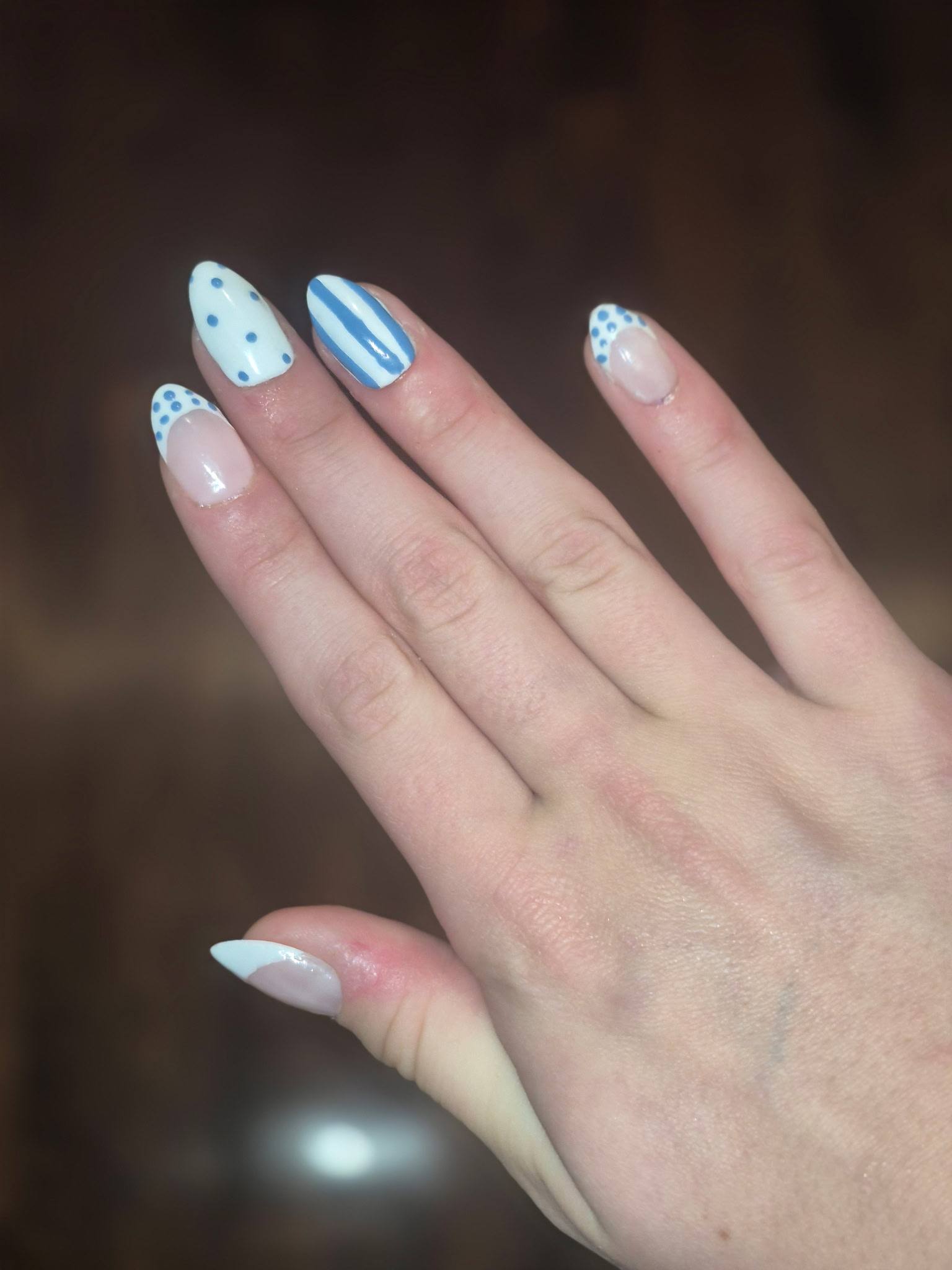 Hand-painted almond nails with blue stripes and polka dots